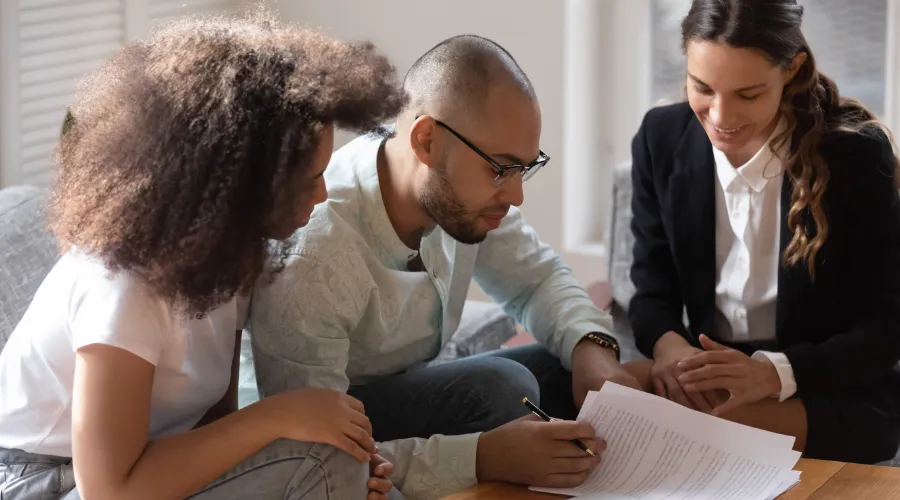 Stock photo of a couple signing forms with a real estate agent.