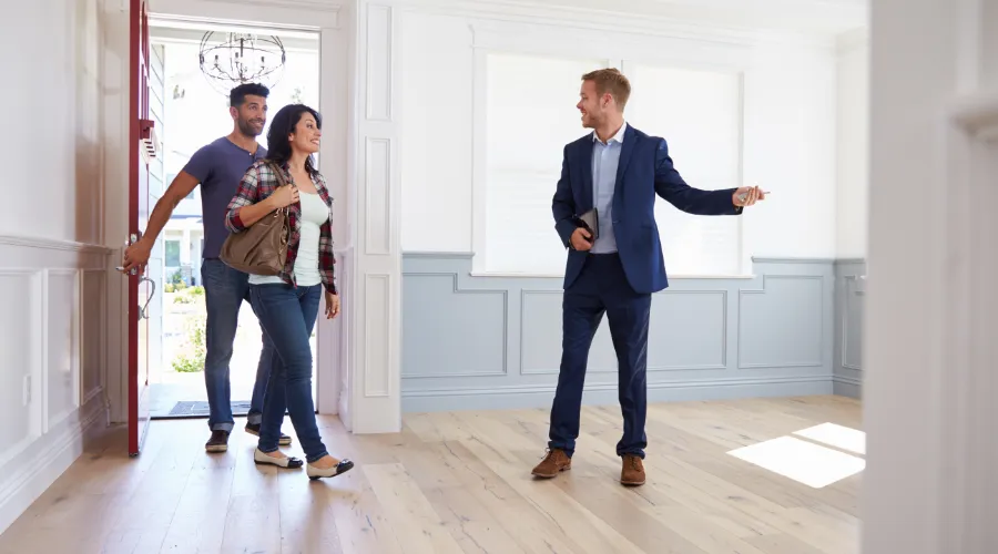Stock photo of a couple and real estate agent entering a house.