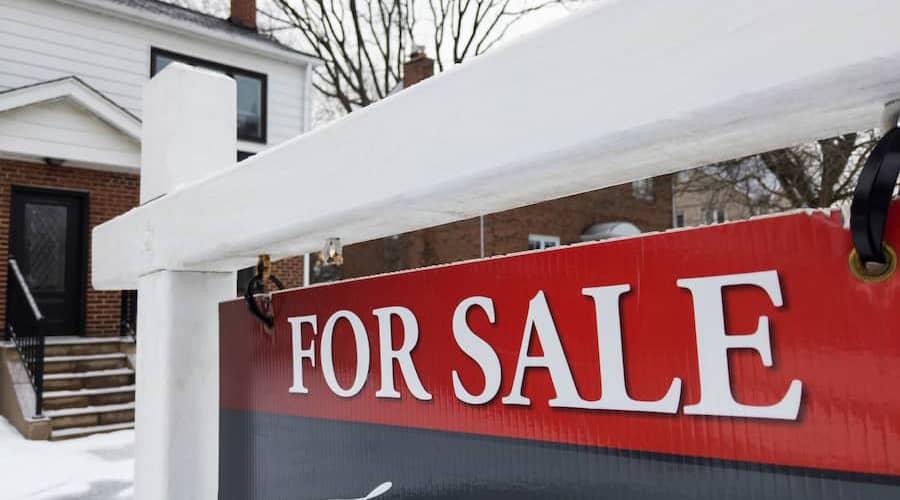 Sign for sale in front of a detached house in residential area. Real estate bubble, new listings, crash, hot housing market, overpriced property, overpaid, buyer activity concept. Selective focus.