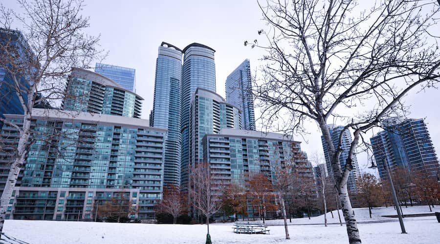 Snowed under park bench in the shadow of tall modern condos in downtown Toronto.